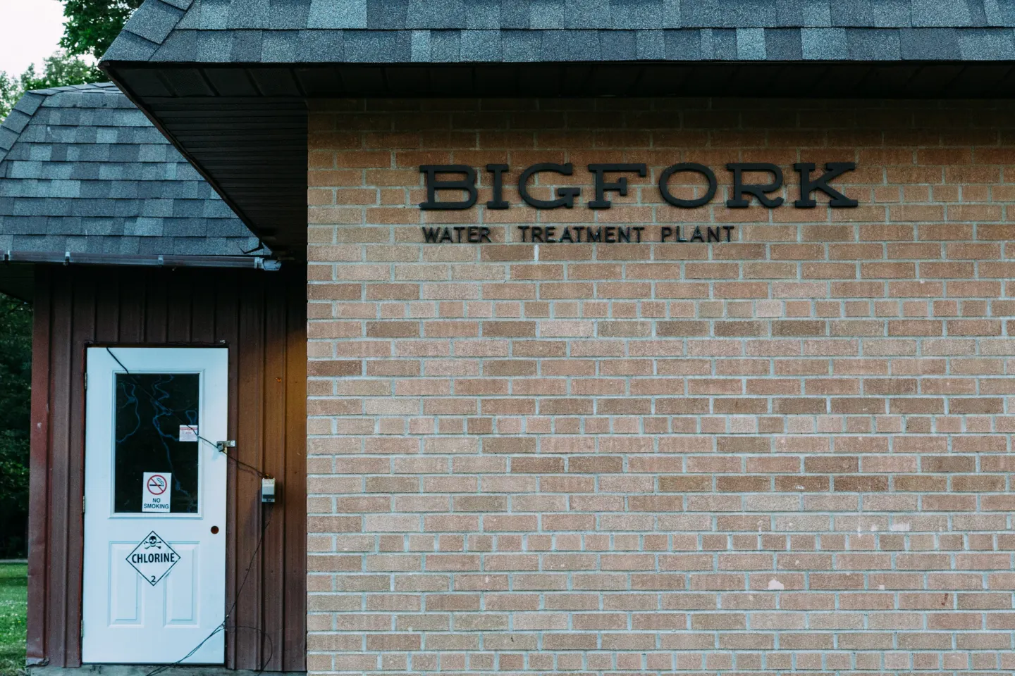 Brick wall of a small building with the sign Bigfork Water Treatment Plant and a white door marked chlorine